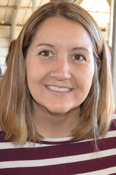 Kathy Barela with light brown hair wearing a maroon and white stripped shirt and smiling.