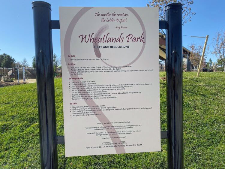 Park rules sign for Wheatlands Park on a grassy area with trees and sky in the background.