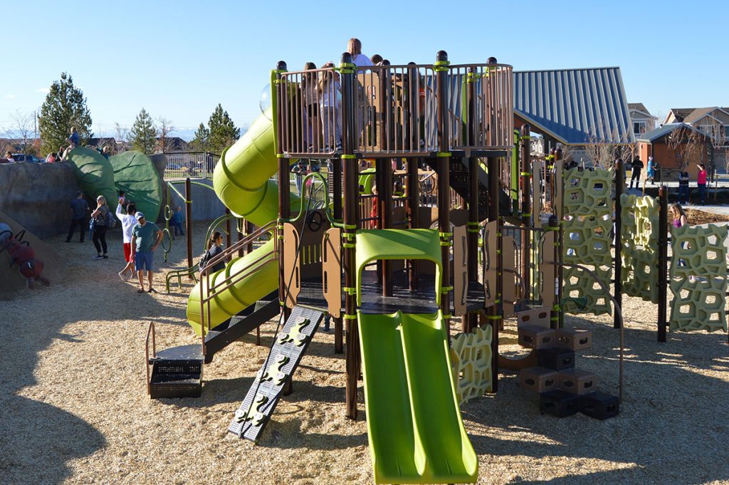 Playground with slides, climbing equipment, and people enjoying the area.