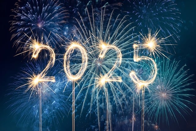 "2025" formed by golden sparklers with colorful fireworks in the background.