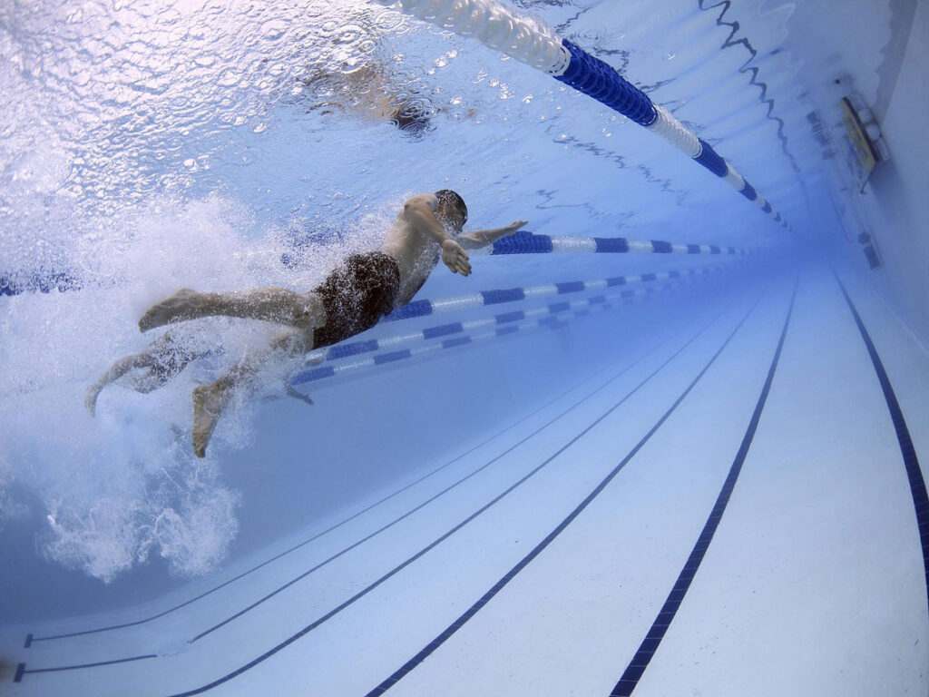 Underwater view of a swimmer doing freestyle in a swimming pool with lane dividers and line markings.